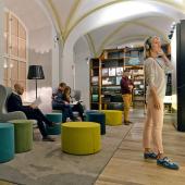 Welttag des Buches; Foto von Menschen in Museumsraum mit bunten Sitzelementen